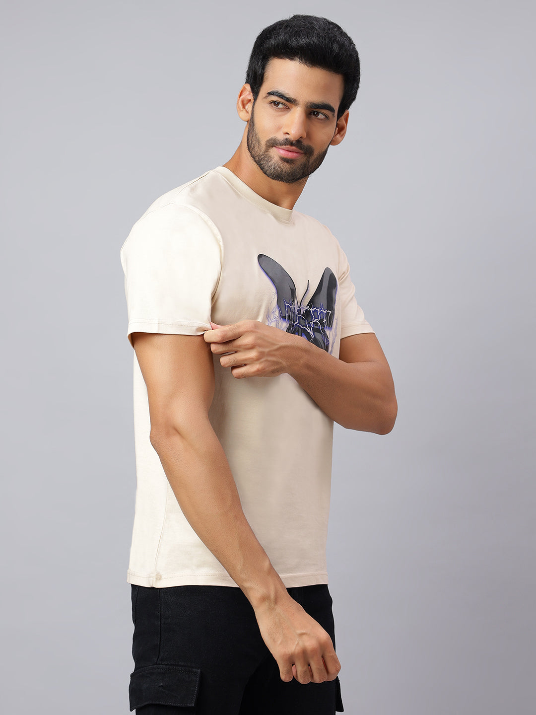 Man wearing a beige t-shirt with a graphic design on a gray background