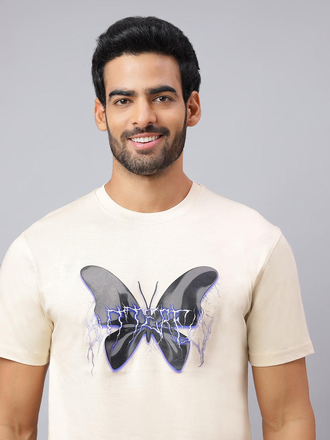 Man wearing a beige t-shirt with a butterfly design on a gray background
