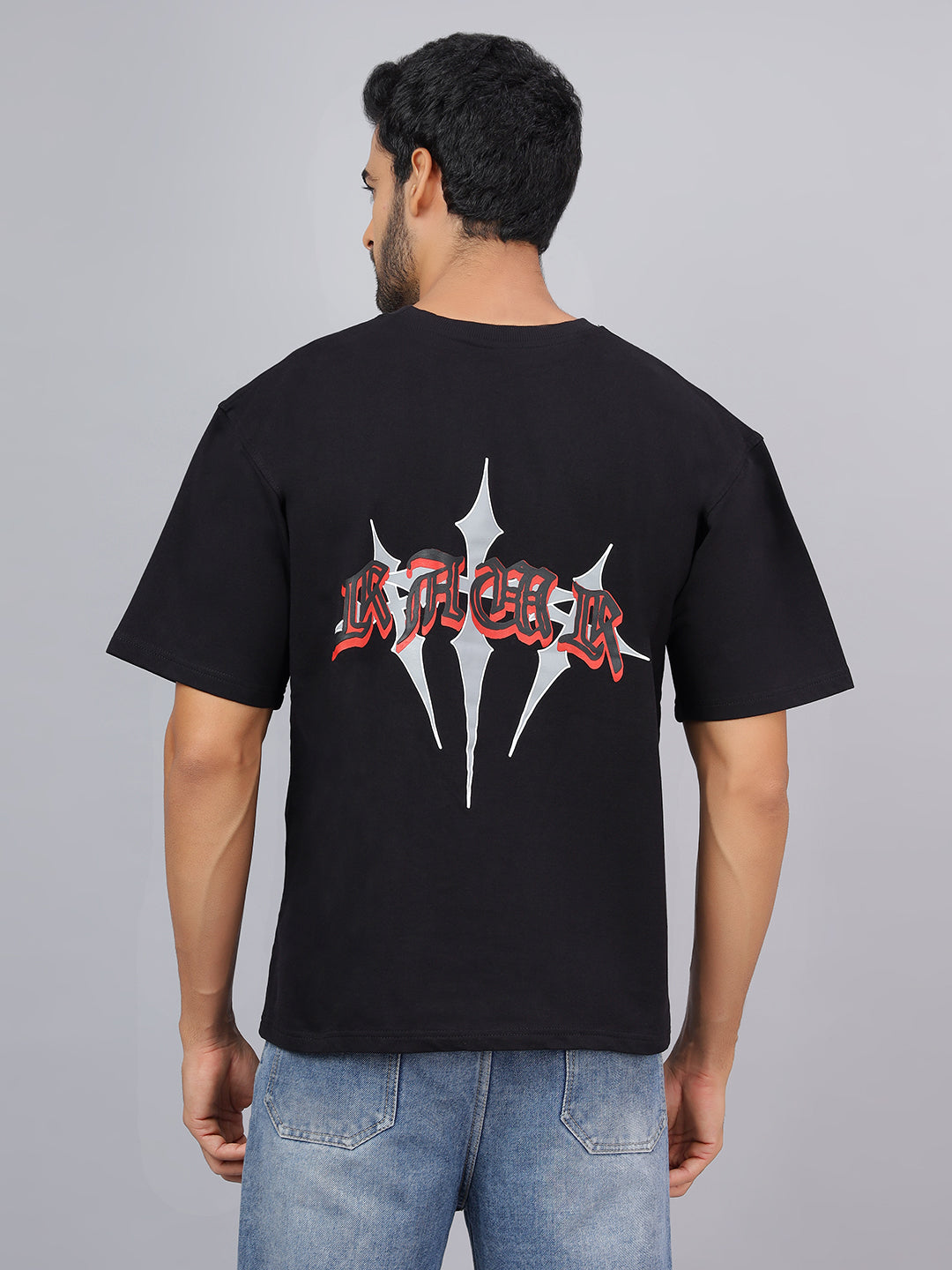 Man wearing a black t-shirt with a logo on the back against a gray background