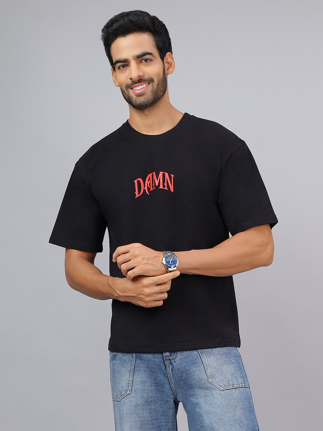 Man wearing a black t-shirt with 'DAMN' in red text on a gray background