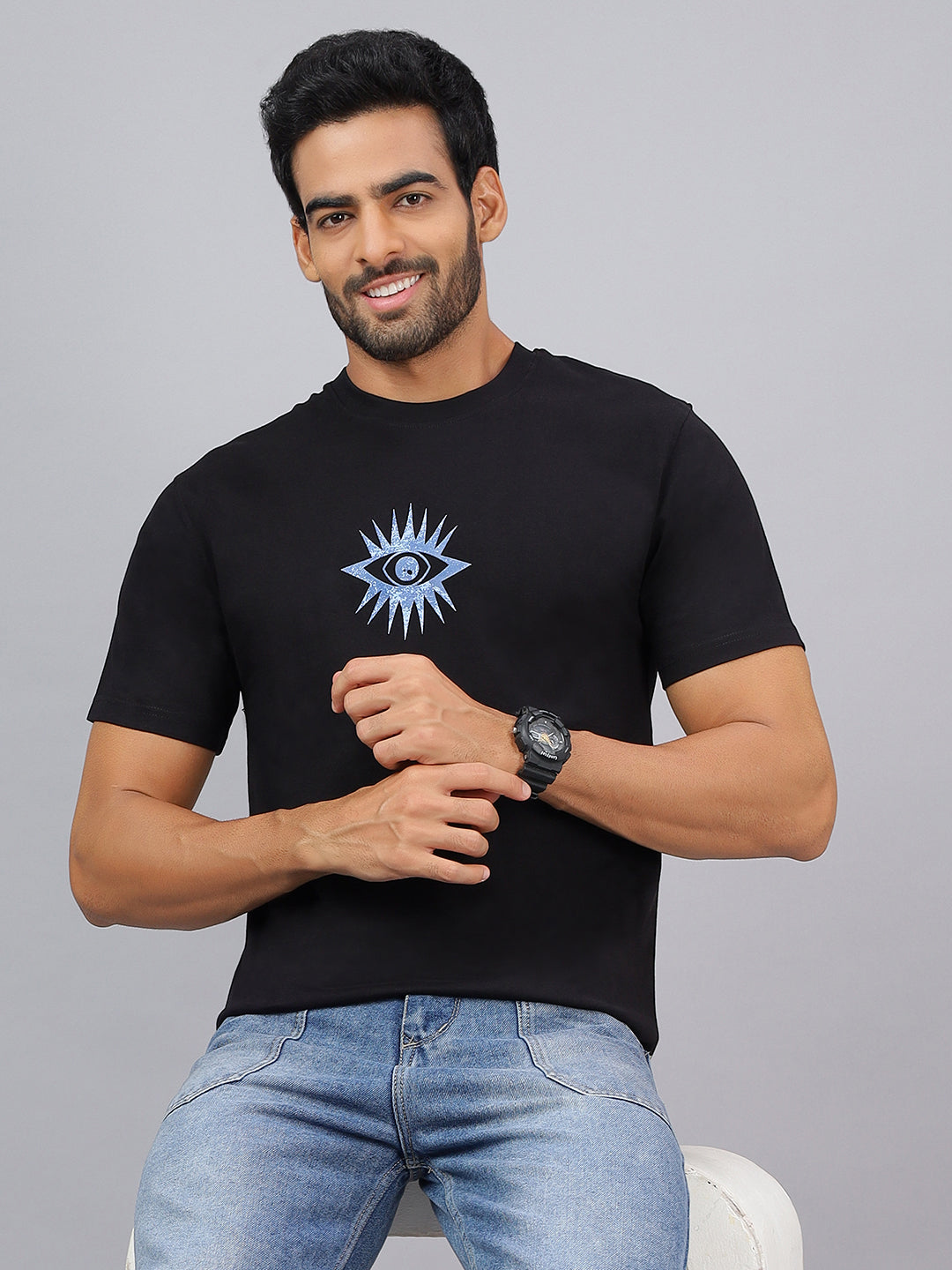 Man wearing a black t-shirt with a blue eye design on a gray background