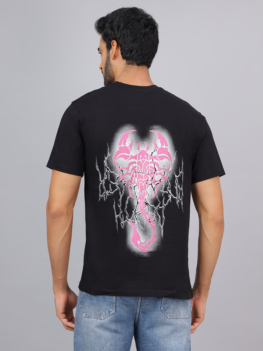 Man wearing a black t-shirt with a pink and gray graphic design on the back against a gray background
