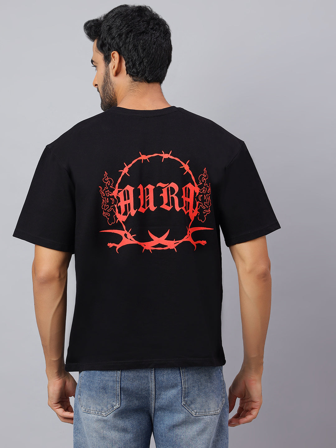 Person wearing a black t-shirt with red logo on the back against a gray background