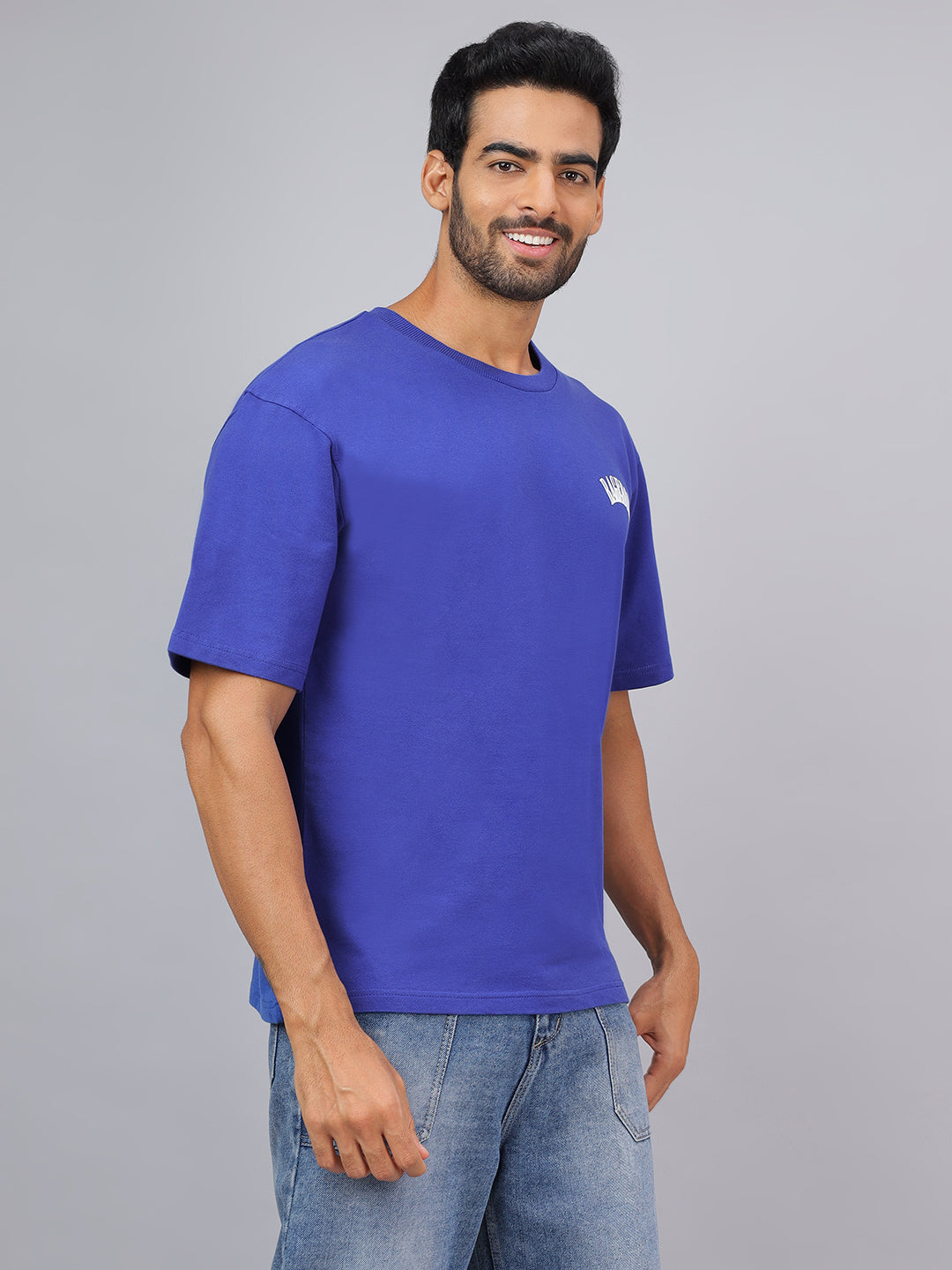 Man wearing a blue t-shirt with a logo on a gray background