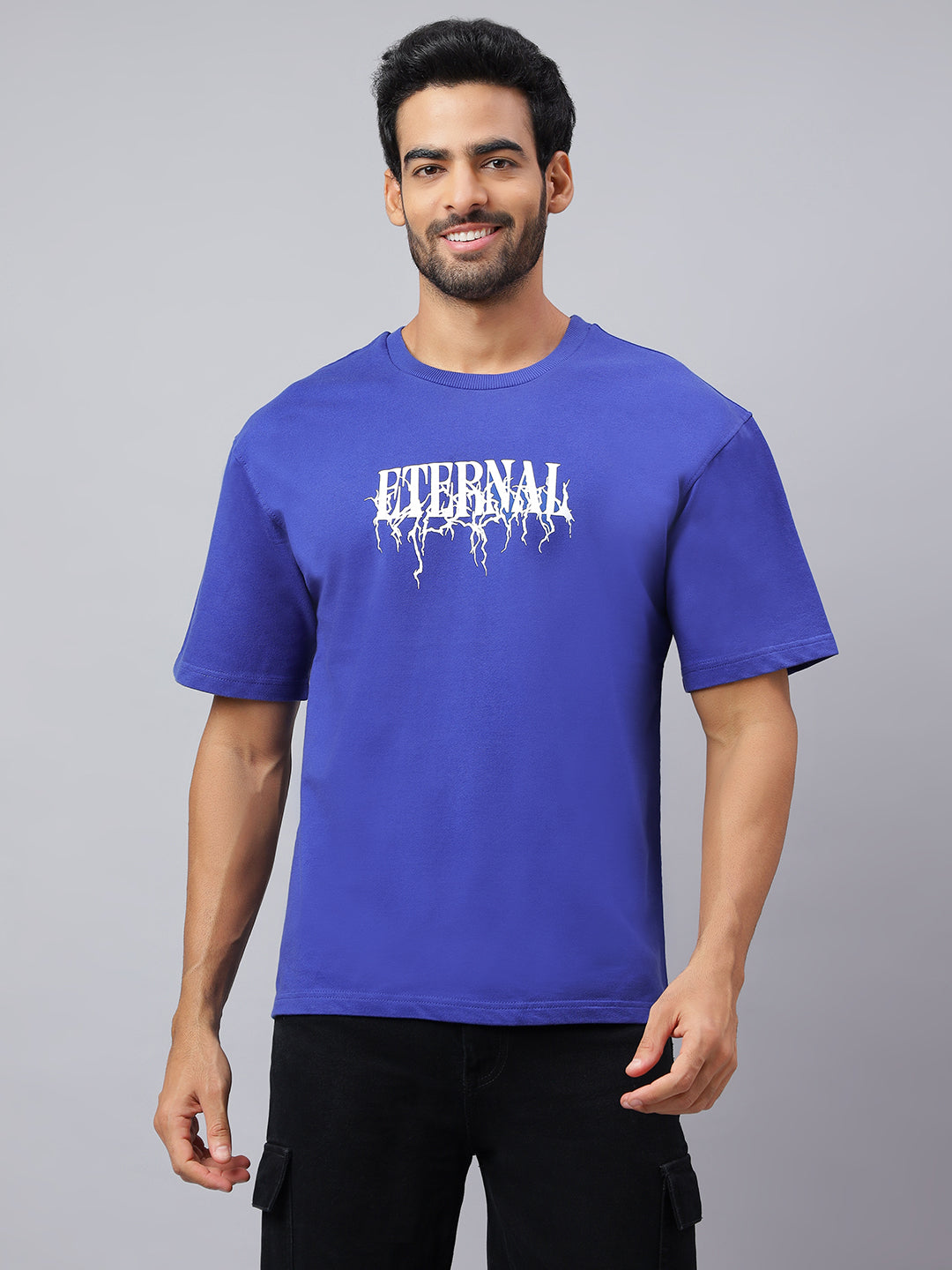 Man wearing a blue t-shirt with 'Eternal' printed on it against a gray background