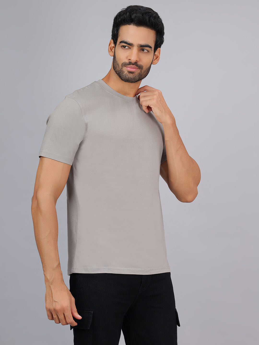 Man wearing a gray t-shirt and black pants on a gray background