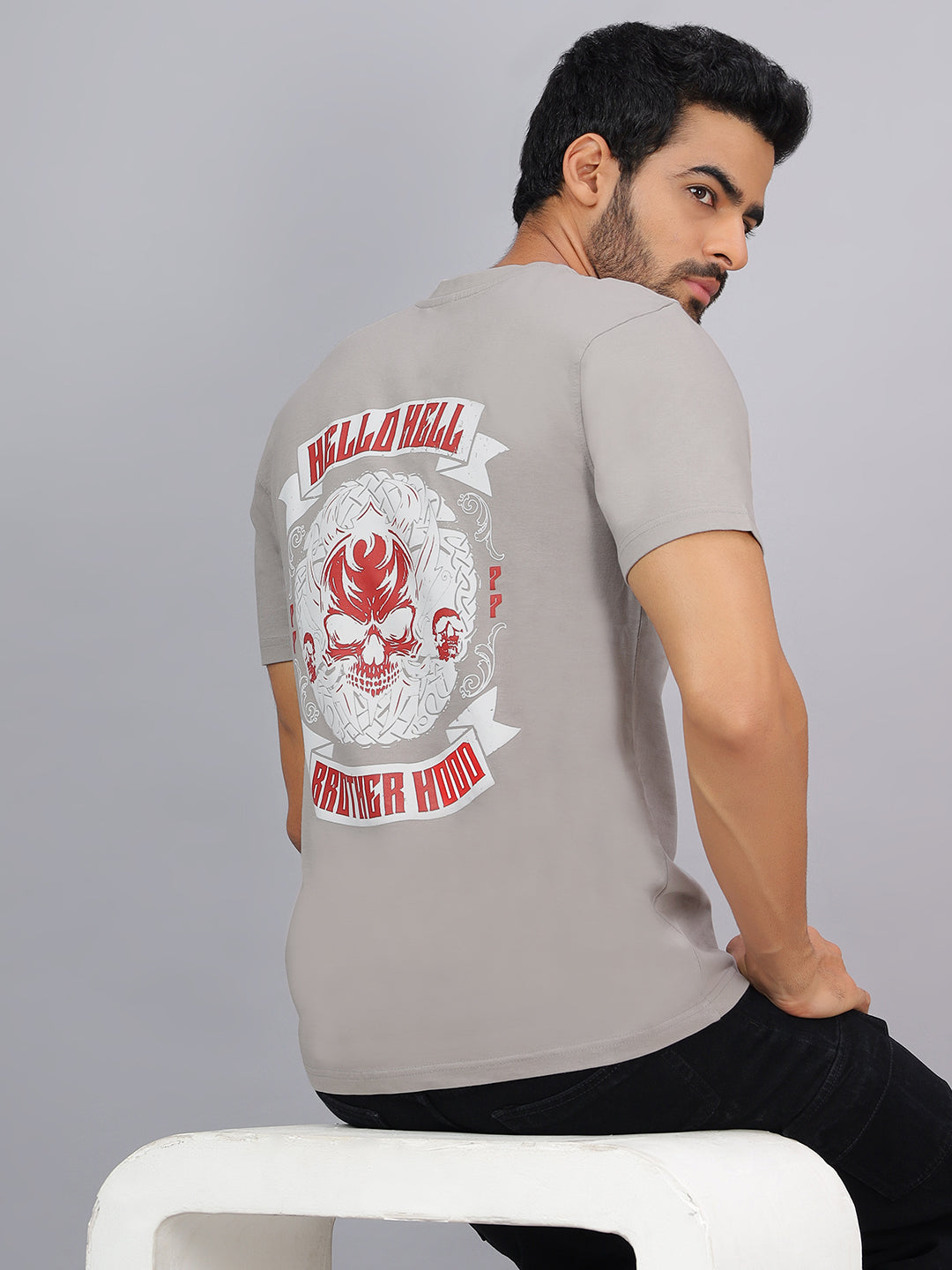 Man wearing a gray t-shirt with a graphic design on the back against a gray background