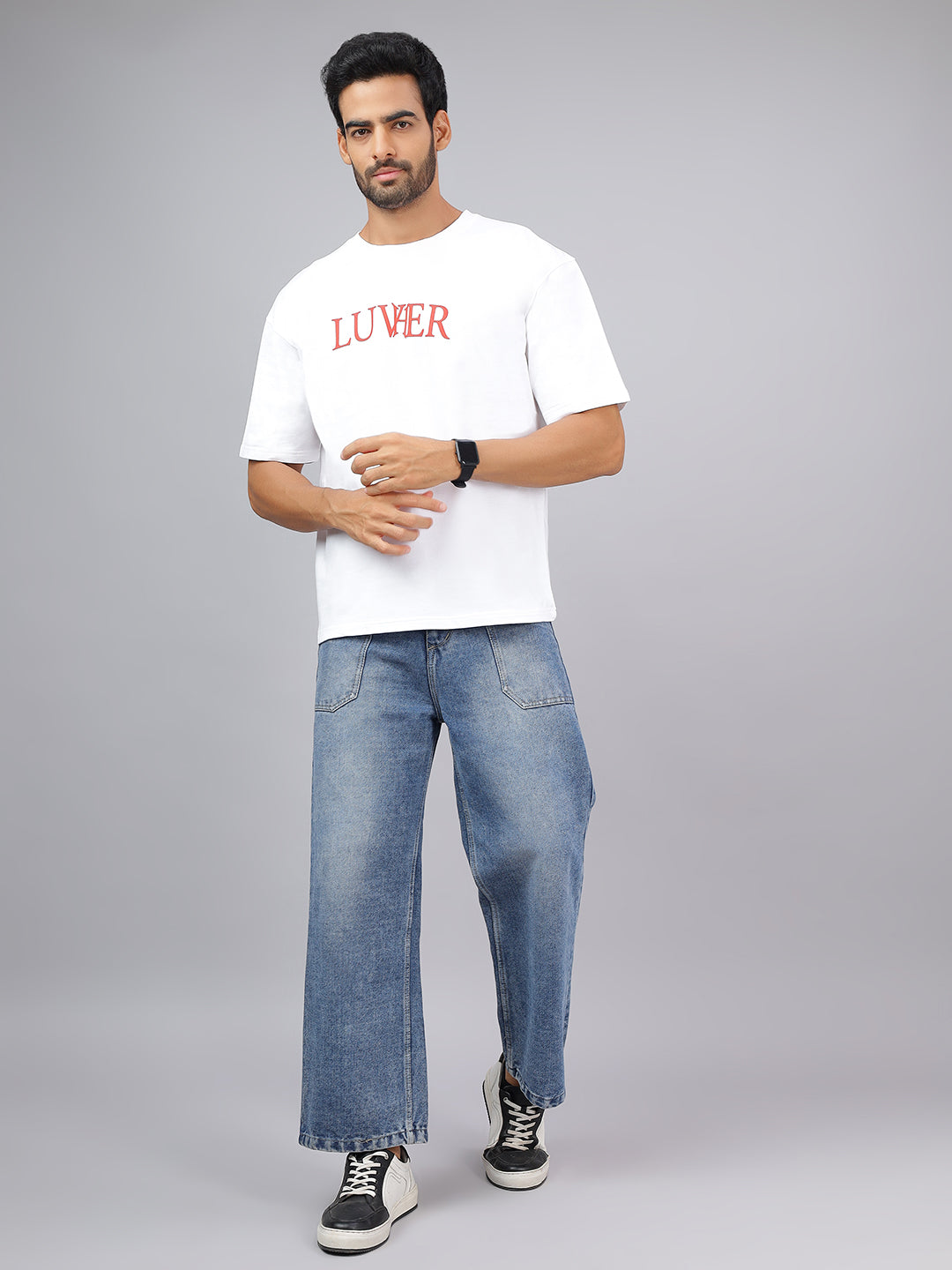 Man wearing a white t-shirt with red text and blue jeans on a gray background